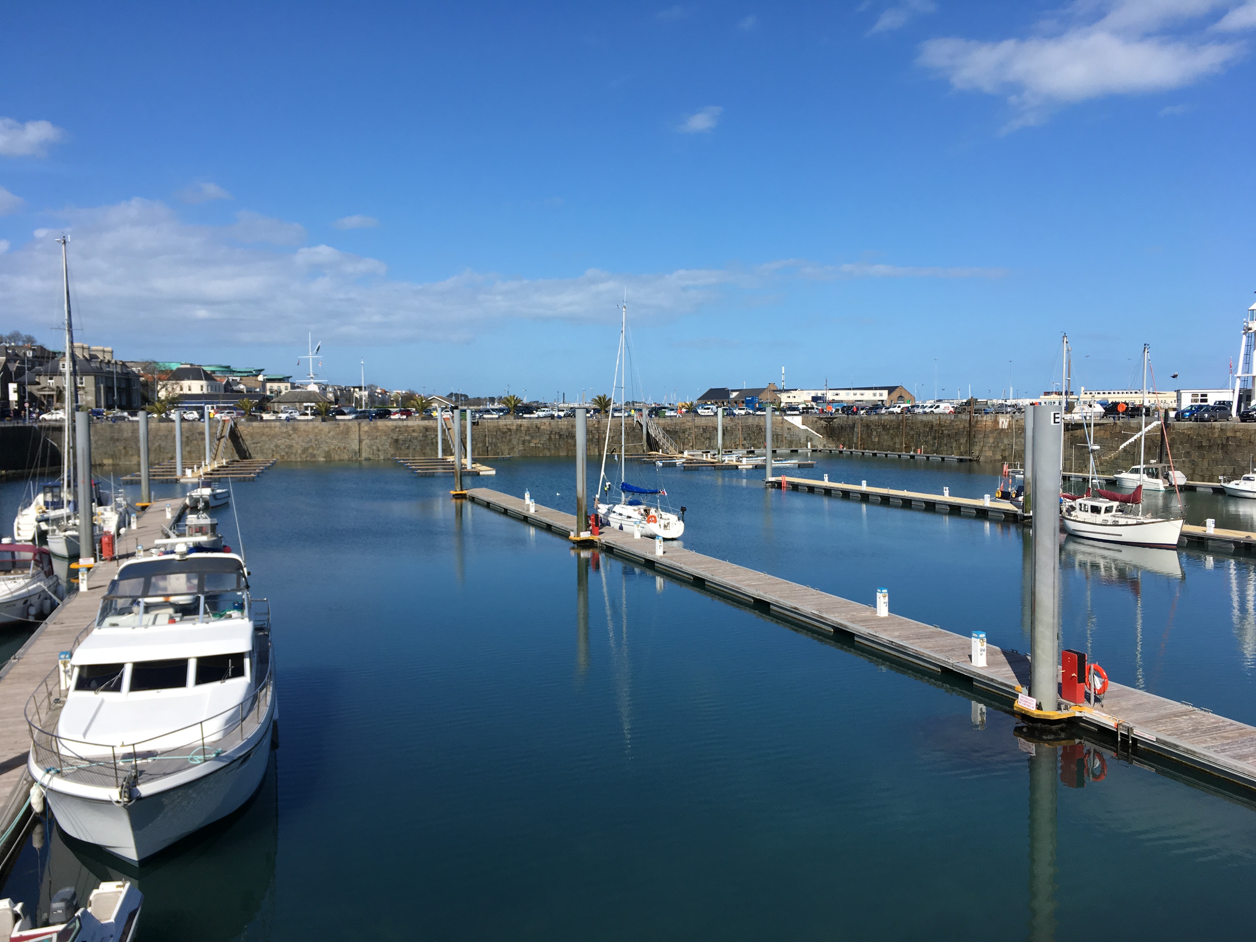 A peaceful bayside with the sun shining on docked boats in Guernsey